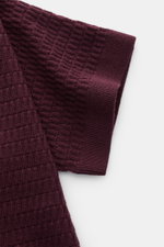 Close-up top-down view of the sleeve of the Emporio Armani Short sleeve jumper burgundy showing textured knit and ribbed band.

Description: Versatile companion: This lightweight short sleeve jumper in pure virgin wool by EMPORIO ARMANI has a subtle textu