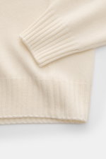 04651/ A trip in a bag Cashmere Rundhalspullover creme, Detailaufnahme von Ärmel und Saum mit feinem Strickbild und Rippbündchen.