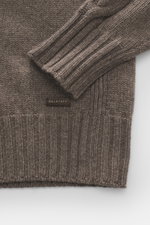 Nahaufnahme des Belstaff Rundhalspullover 'Harrow' taupe in Slim Fit, reine Wolle, weicher Griff, klassischer Zopfstrick, Raglanärmel, mit BELSTAFF-Patch am Saum, flexible Rippbündchen, mittelgrobes Strickbild, von oben fotografiert.