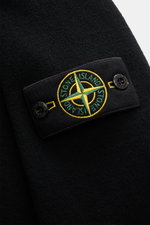 Nahaufnahme des Stone Island Rundhalspullover schwarz, Fokus auf das markentypische Kompass-Badge aus Wollmix mit feinem Strickbild.
