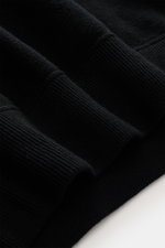 Close-up angled view of the Stone Island Black crew neck sweater showing the soft virgin wool and microfiber knit fabric with ribbed cuffs.