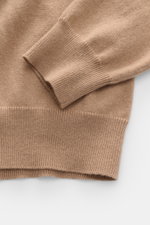 Nahaufnahme des hellbraunen Malo Cashmere Rundhalspullover-Ärmels mit feinem Strickbild, Regular Fit, Rundhalsausschnitt und Rippbündchen, fotografiert von schräg oben.