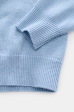 Nahaufnahme des Malo Cashmere Rundhalspullovers hellblau in Slim Fit, fotografiert von schräg oben, zeigt mittelfeines Strickbild und breite Rippbündchen aus reinem, sehr weichem Cashmere.