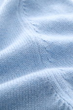 Nahaufnahme des hellblauen Malo Cashmere Rundhalspullover mit mittelfeinem Strickbild, weichem Griff und komfortablen Rippbündchen, fotografiert aus schräger Perspektive.