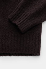 Drumohr Rundhalspullover dunkelbraun aus reiner Lammwolle, Detailaufnahme von Ärmel und Bund, weicher Griff, feines Strickbild, Rippbündchen.
