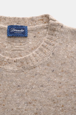 Nahaufnahme des beigen melierten Drumohr Rundhalspullover Slim Fit mit Rundhalsausschnitt und flexiblen Rippbündchen, mittelfeines Strickbild, Mix aus Schurwolle, Cashmere und Microfaser, sehr weicher Griff, von oben fotografiert.