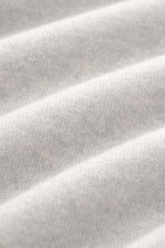 Close-up view of the fine knit pattern of the Gran Sasso Cashmere crew neck sweater light grey melange, showcasing pure cashmere with a very soft feel, photographed from above, highlighting the regular fit, crew neckline, and comfortable ribbed cuffs.