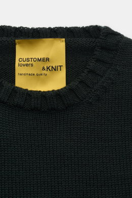 Close-up front view of the B.F. Knitwear Merino crew neck jumper dark green showing rib knit bands and label, pure merino wool, soft feel, semi chunky knit, slim fit, crew neck.