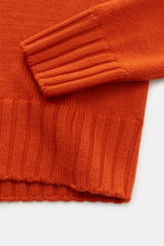 Close-up image of the sleeve and hem of the B.F. Knitwear Merino crew neck jumper orange, showing pure merino wool, soft feel, semi chunky knit, slim fit, crew neck, and rib knit bands from a top-down perspective.