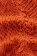 Close-up image from an angled top view of B.F. Knitwear Merino crew neck jumper orange, showing semi chunky knit texture with rib knit bands, pure merino wool, soft feel, slim fit, and crew neck details.