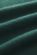 Close-up texture of the B.F. Knitwear Cashmere crew neck sweater dark green, photographed from a macro perspective showing pure cashmere, soft touch, medium-fine knit, slim fit, crew neckline, and elastic ribbed cuffs, perfect for autumn, made in Italy.