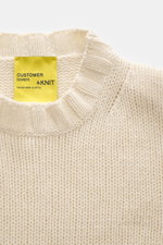 Close-up top-down view of B.F. Knitwear Cashmere crew neck sweater cream showing soft pure cashmere, medium coarse knit, elastic ribbed cuffs, and crew neckline.