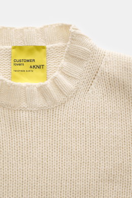 Close-up top-down view of B.F. Knitwear Cashmere crew neck sweater cream showing soft pure cashmere, medium coarse knit, elastic ribbed cuffs, and crew neckline.
