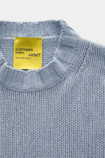 Close-up front view of B.F. Knitwear Cashmere crew neck sweater light blue melange showing medium coarse knit, elastic ribbed cuffs, and label. Autumnal cashmere from the knitting expert B.F. KNITWEAR: This softly knitted crew neck sweater is the perfect 