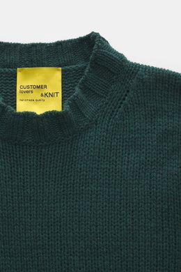 B.F. Knitwear Cashmere crew neck sweater dark green shown from above, highlighting medium coarse knit, elastic ribbed cuffs, and crew neckline. Autumnal cashmere from the knitting expert B.F. KNITWEAR: This softly knitted crew neck sweater is the perfect 
