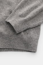 Nahaufnahme des Aida Barni Cashmere Rundhalspullover grau meliert, Fokus auf feines Strickbild, weicher Griff und Rippbündchen, seitliche Perspektive.