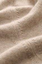 Alt-Tag (124 Zeichen):
Nahaufnahme des fein gestrickten, beige melierten Brunello Cucinelli Cashmere Rundhalspullovers, Fokus auf weiche Textur.