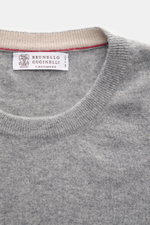Close-up front view of Brunello Cucinelli Cashmere pullover grey melange showing fine knit crew neck with narrow contrast-coloured edges.

Additional description: <p>This timeless and versatile finely knit crew neck sweater by BRUNELLO CUCINELLI is made f