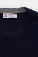 Close-up top-down view of Brunello Cucinelli Cashmere pullover navy crew neck sweater showing pure cashmere knit, fine texture, and narrow contrast edges.