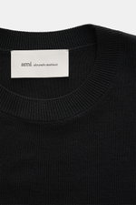 Ami Paris Merino Crew Neck Sweater Black shown from top close-up, featuring pure merino wool, soft touch, fine knit, crew neckline, ribbed cuffs, and logo stitching.