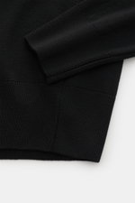 A close-up front view of the Ami Paris Merino Crew Neck Sweater Black showing the fine knit pattern, ribbed cuffs, and hem made from pure merino wool, soft touch, regular fit, crew neckline, and logo stitching on the chest. Timeless basic: The AMI PARIS c