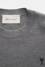 Nahaufnahme des Ami Paris Merino Rundhalspullover grau meliert von oben, zeigt feines Strickbild, weichen Griff, Rundhalsausschnitt, Rippbündchen und Logo-Stitching. Zeitloses Basic aus reiner Merinowolle, Regular Fit, ideal für Büro und Freizeit.