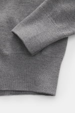 Nahaufnahme des Ärmel- und Saumbereichs vom Ami Paris Merino Rundhalspullover grau meliert, aus reiner Merinowolle mit feinem Strickbild, weichem Griff, Regular Fit, Rundhalsausschnitt, Logo-Stitching auf der Brust und komfortablen Rippbündchen, fotografi