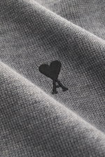 Nahaufnahme des Ami Paris Merino Rundhalspullover grau meliert aus reiner Merinowolle mit feinem Strickbild und Logo-Stitching auf der Brust.