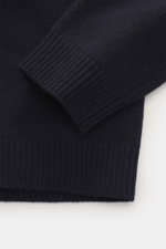 Maison Kitsuné Rollkragenpullover navy aus reiner Wolle mit weichem Griff, mittelfeinem Strickbild, Rippbündchen, hoher Kragen, Detailaufnahme von Ärmel und Saum.