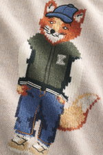 Maison Kitsuné Rundhalspullover sand meliert mit Fuchs-Intarsienstrick, weichem Griff, mittelfeinem Strickbild, von schräg oben fotografiert.
