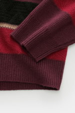 Nahaufnahme von Ärmel und Bund des Guest In Residence Cashmere Rundhalspullover schwarz/rot/violett gestreift, mittelfeines Strickbild, weicher Griff, Oversized Fit, reiner Cashmere, Rundhalsausschnitt, fotografiert von oben.