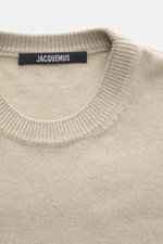 Jacquemus Merino crew neck sweater beige melange shown from above, featuring elastic merino wool, soft touch, medium-fine knit pattern, regular fit, crew neckline, logo detail on the back, and comfortable ribbed cuffs.