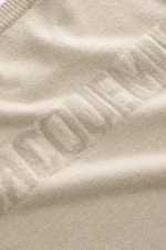 Close-up top-down view of Jacquemus Merino crew neck sweater beige melange showing elastic merino wool, soft touch, medium-fine knit pattern, regular fit, crew neckline, logo detail on the back, and comfortable ribbed cuffs.