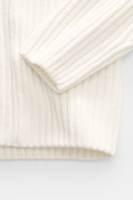 Nahaufnahme des cremefarbenen C.P. Company Rundhalspullover aus reiner Baumwolle, weiche Qualität, mittelfeines Rippstrickbild, Slim Fit, Raglanärmel, Ärmel-Tasche und Linsen-Detail, fotografiert von oben.