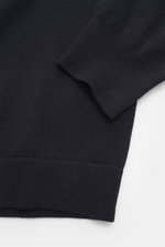 Nahaufnahme des C.P. Company Rundhalspullover navy von schräg oben, Mix aus Schurwolle und Microfaser, weicher Griff, feines Strickbild, Slim Fit, Rundhalsausschnitt, Tasche mit Druckknopf am Oberarm, labeltypisches Linsen-Detail, flexible Rippbündchen.