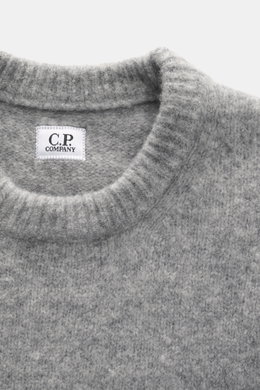 Nahaufnahme aus Draufsicht des C.P. Company Rundhalspullover grau meliert, mit mittelfeinem Strickbild, weichem Griff, Slim Fit, elastischer Qualität, Zipper-Tasche am Oberarm, flexible Rippbündchen, Linsen-Detail, Mix aus Wolle und Microfaser.