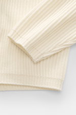 Nahaufnahme des C.P. Company Rundhalspullover creme von schräg oben, mittelfeines Strickbild, Patent-Strickmuster, weicher Griff, flexible Rippbündchen.