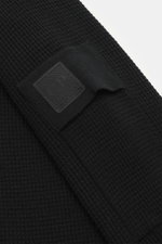 Nahaufnahme des Ärmels mit Ärmeltasche und Logo-Patch des C.P. Company Rundhalspullover 'Metropolis' schwarz, Waffelstrick aus Schurwolle und Microfaser, feines Strickbild, kerniger Griff, Regular Fit, Rundhalsausschnitt, flexible Rippbündchen, seitliche 
