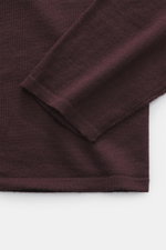 Close-up top-down view of the burgundy Kiefermann Merino Crewneck Sweater 'Marleys' sleeve and body, showing fine knit, slim fit, and soft touch.
