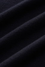Close-up, angled view of navy fabric texture showing very fine knit pattern of Kiefermann Merino Fine Knit Sweater 'Benjaminn' navy, made of pure merino wool, super soft feel, slim fit, round neckline, and open, rolled edge finishes.