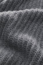 Nahaufnahme des grob gestrickten, dunkelgrauen Kiefermann Rundhalspullovers 'Siomann' mit weichem Griff, aufgenommen aus schräger Perspektive.