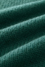 Close-up, angled view of the green Iris von Arnim Cashmere-silk crew neck sweater "Felton," showing a voluminous knit pattern, mix of cashmere and silk, very soft feel, slim fit, crew neckline, and comfortable ribbed cuffs.