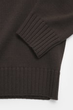 Nahaufnahme des dunkelbraunen Filippo de Laurentiis Merino Rundhalspullovers von schräg oben, zeigt weichen Griff, feines Strickbild und flexible Rippbündchen.