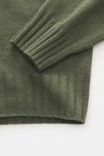 Nahaufnahme des dunkelgrünen Allude Rundhalspullovers mit weichem Griff, mittelgrobem Strickbild, Regular Fit, Rundhalsausschnitt und Rippbündchen, fotografiert von oben. Mix aus Wolle und Cashmere.