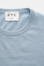 Close-up top view of FTC Cashmere Crew Neck Sweater light blue showing pure cashmere fabric, fine knit pattern, crew neckline, and ribbed cuffs, slim fit.