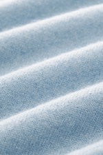 Close-up, angled view of the FTC Cashmere Crew Neck Sweater light blue showing pure cashmere, very soft touch, fine knit pattern, slim fit, crew neckline, and ribbed cuffs.