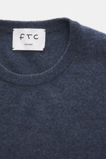 Nahaufnahme aus schräger Draufsicht auf den Rundhalsausschnitt des FTC Cashmere Rundhalspullover graublau meliert aus reinem, ultraweichem Cashmere mit feinem Strickbild und Rippbündchen.