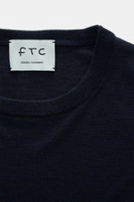 Nahaufnahme des FTC Feinstrick-Rundhalspullover navy mit Rundhalsausschnitt, Slim Fit, weichem Griff, feinem Strickbild, Rippbündchen, Mix aus Cashmere und Lyocell, OEKO-TEX® Standard 100 zertifiziert, von oben fotografiert.