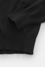 Nahaufnahme des Ärmels und Bunds vom BRAUN Hamburg Cashmere Rundhalspullover schwarz, feines Strickbild, Slim Fit, weicher Griff, flexible Rippbündchen.