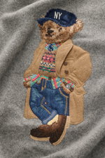 Nahaufnahme des Polo Ralph Lauren Rundhalspullover grau meliert mit ikonischer Polo-Bear-Intarsie, gestrickt aus Wolle und Cashmere, weicher Griff, mittelfeines Strickbild, Rundhalsausschnitt, Regular Fit, Rippbündchen, Initial-Stitching am Saum, aus fron